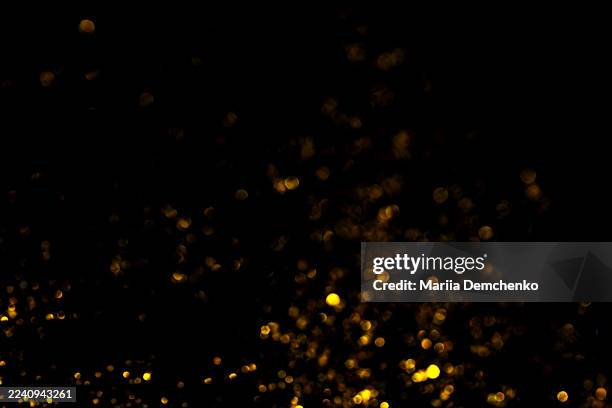 gold bokeh lights on black background. glitter sparkle stars overlay - scattered stock pictures, royalty-free photos & images