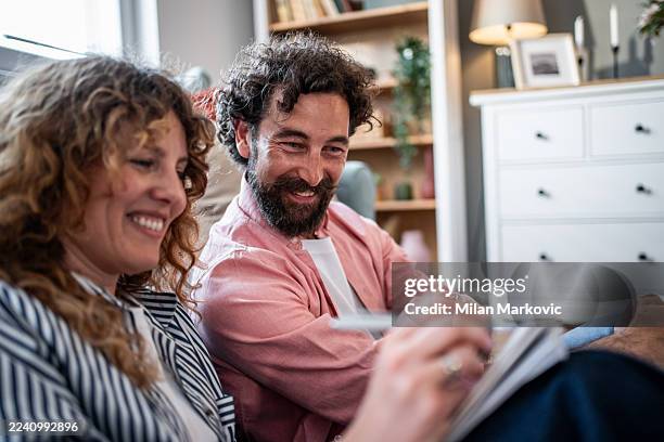 happy couple drawing together, enjoying leisure time at home - mid adult couple stock pictures, royalty-free photos & images