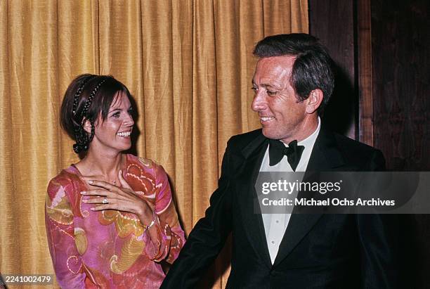 Franco-American singer, actress and dancer Claudine Longet, wearing a pink, yellow and red outfit, and her husband, American singer Andy Williams,...