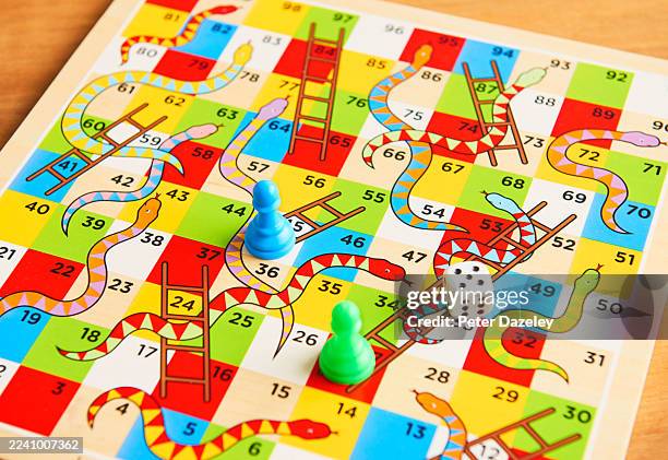 dice on snakes and ladders board. - snakes ladders stock pictures, royalty-free photos & images