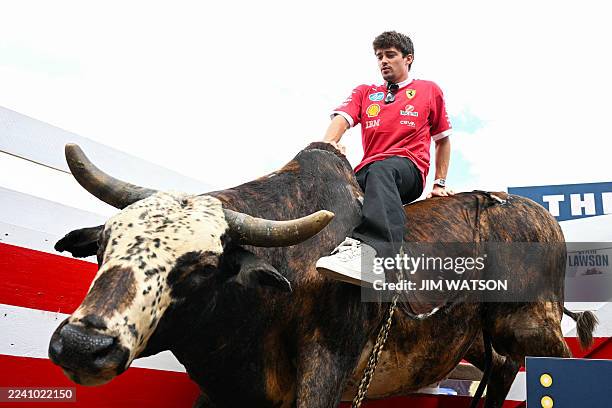 Ferrari's Monegasque driver Charles Leclerc sits on an artificial bull in the paddock ahead of the United States Formula One Grand Prix at the...