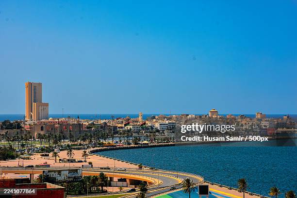 high angle view of a coastal city with buildings, a winding road, and the sea under a clear blue sky,libya - libia fotografías e imágenes de stock