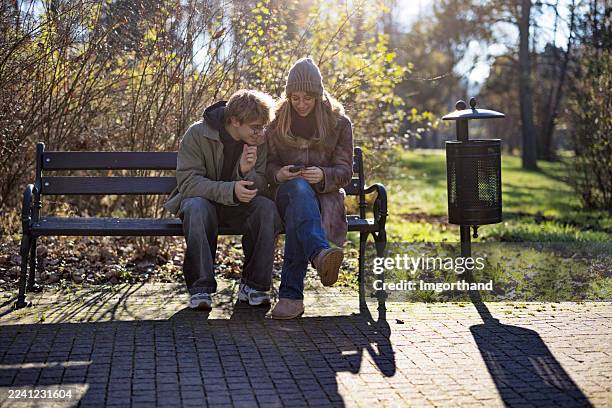 two teenage friends enjoying sunny autumn day in public park - careless stock pictures, royalty-free photos & images