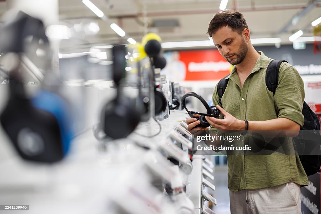 Male customer choosing headphones in tech store