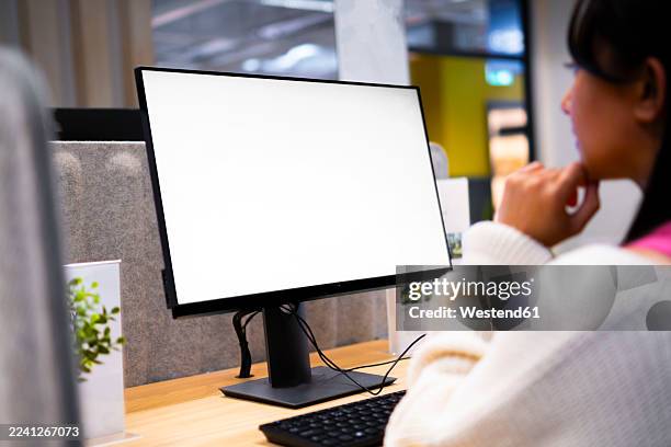 woman relaxing at modern office desk with computer monitor indoors - blank screen stock pictures, royalty-free photos & images