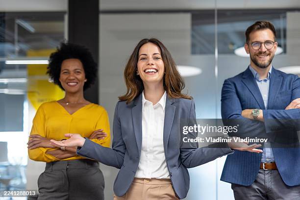smiling businesspeople posing in modern office welcoming clients - gelijkwaardige behandeling stockfoto's en -beelden