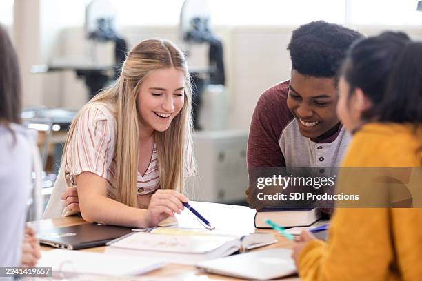 diverse group of young adults collaborating and laughing together during a study session - middelbare scholier stockfoto's en -beelden