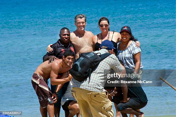Actor Pierce Brosnan standing next to wife Keely Shaye Smith poses for a photograph at the water's edge with crew members of the Polynesian Voyaging...
