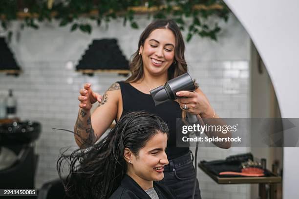 stilista donna che soffia i capelli della donna in un salone - salone di parrucchiere foto e immagini stock