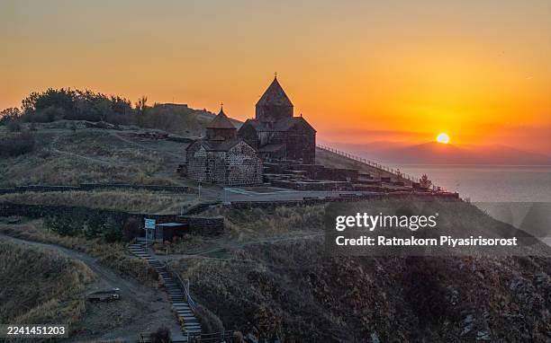 the historic 9th-century sevanavank monastery, an iconic landmark on the shores of lake sevan, armenia, is silhouetted against a spectacular golden sunrise. - sevanavank monastery stock pictures, royalty-free photos & images