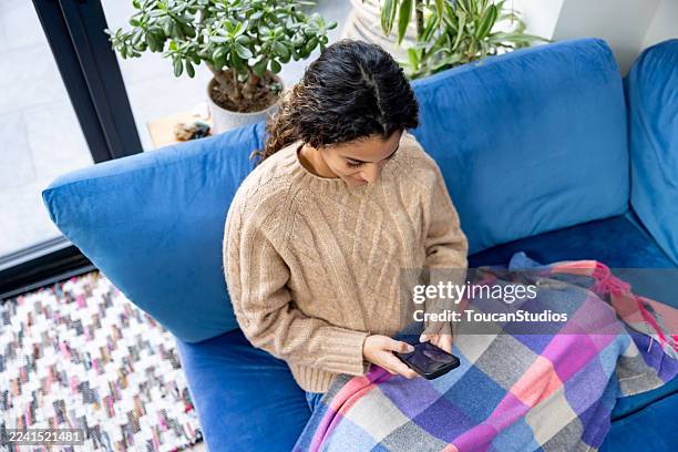 glückliche frau zu hause blick auf social media auf ihrem handy - krankenstand stock-fotos und bilder