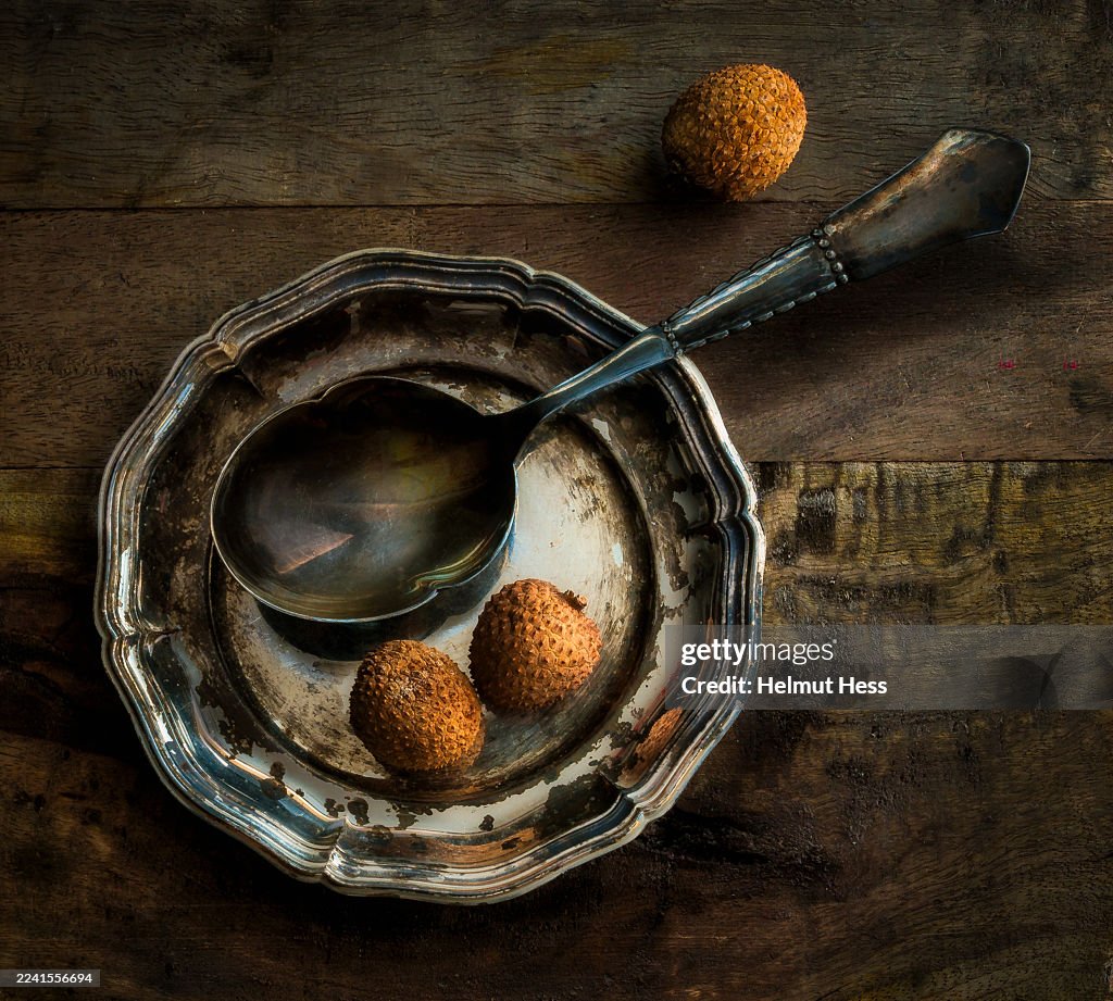 Still life with lychees, old silver plate and spoon