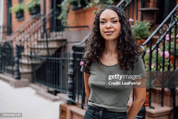 natural lifestyle portrait of a woman walking through a city neighborhood - west village stock pictures, royalty-free photos & images