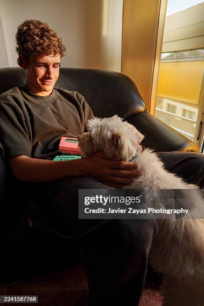 teenager relaxing with dog, listening to retro music - warmes licht stock-fotos und bilder