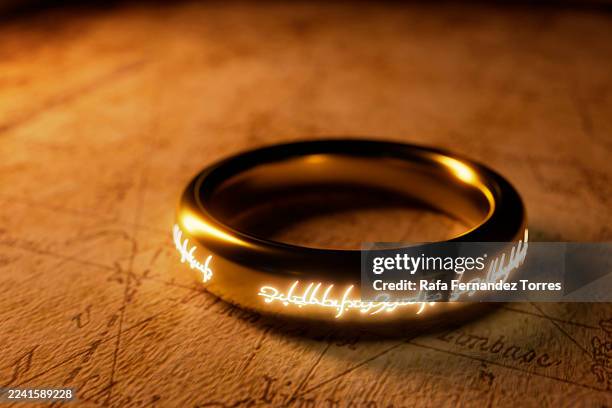golden ring with glowing runes on vintage map surface. - bague photos et images de collection