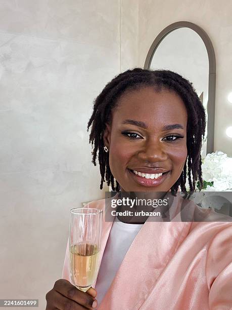 junge schwarze frau, die selfies macht, während sie champagner trinkt, nachdem sie sich in einem schönheitssalon schminken lässt - permanent make up stock-fotos und bilder