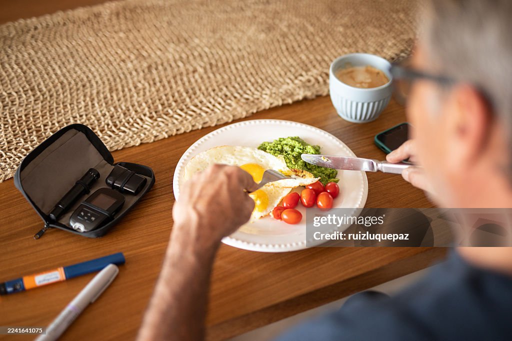 Homem diabético maduro comendo após injetar insulina