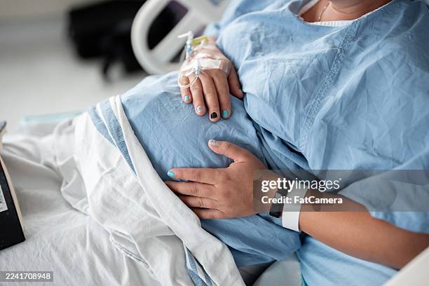 werdende mutter im krankenhausbett, die während der wehen und geburt vom partner unterstützt wird - entbindungsstation stock-fotos und bilder