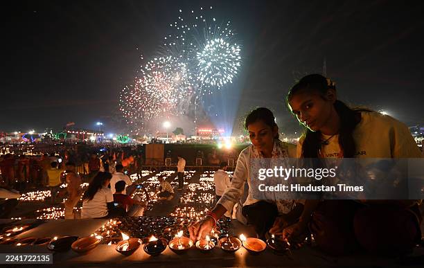 People lighting the earthen lamps at Ram ki Pedi during grand Deepotsav Celebration on October 19, 2025 in Ayodhya, India. 26.17 lakh diyas were lit...