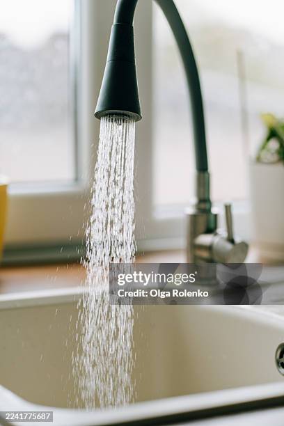 faucet pouring fresh water into kitchen sink - running water stock pictures, royalty-free photos & images