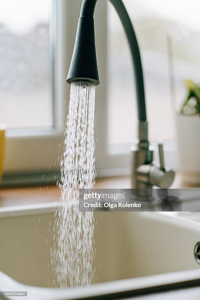 Faucet pouring fresh water into kitchen sink