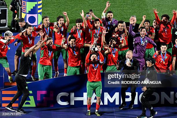 Morocco's midfielder Houssam Essadak holds the trophy while celebrating with teammantes after winning the 2025 FIFA U-20 World Cup final football...