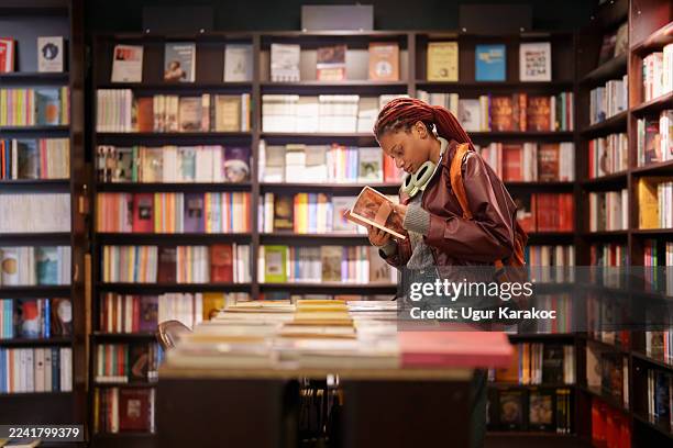 frau liest ein buch in einem gang einer buchhandlung - buchhandlung stock-fotos und bilder