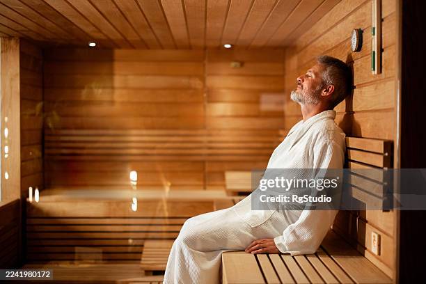 uomo che si rilassa in sauna godendo di calore e benessere - accappatoio foto e immagini stock