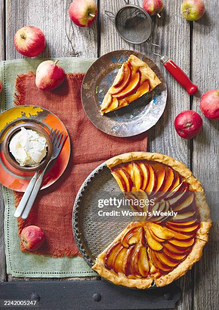 Caramel Apple Tart, apple tart with slices removed, with a single slice on a plate, and cream in a bowl on a plate with two forks.