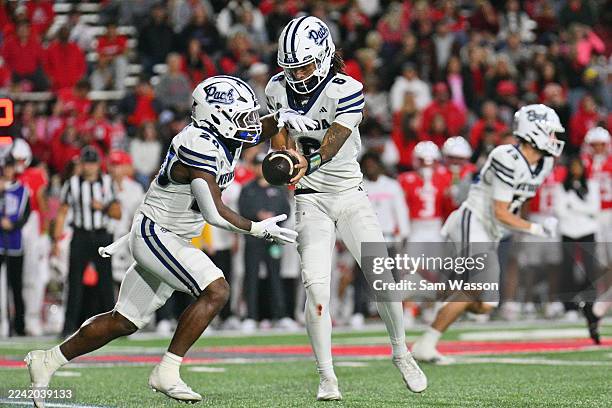 Quarterback Carter Jones of the Nevada Wolf Pack hands off to running back Caleb Ramseur during the first half of a game against the New Mexico Lobos...