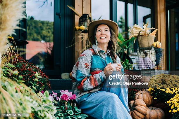 woman enjoying autumn morning with coffee on porch - harvest festival stock pictures, royalty-free photos & images