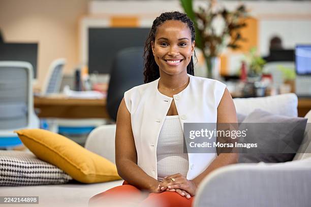 confident female business professional sitting on sofa - hand op knie stockfoto's en -beelden
