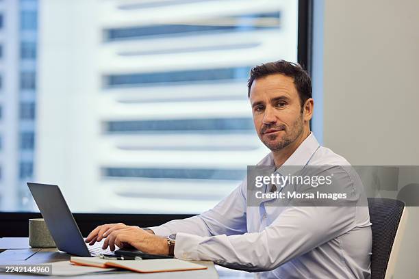 male entrepreneur sitting at desk in office - solo un uomo maturo foto e immagini stock