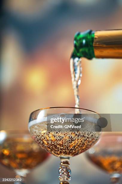 champagner in champagnerflöten gießen für die weihnachtsfeiertage - schaumwein stock-fotos und bilder