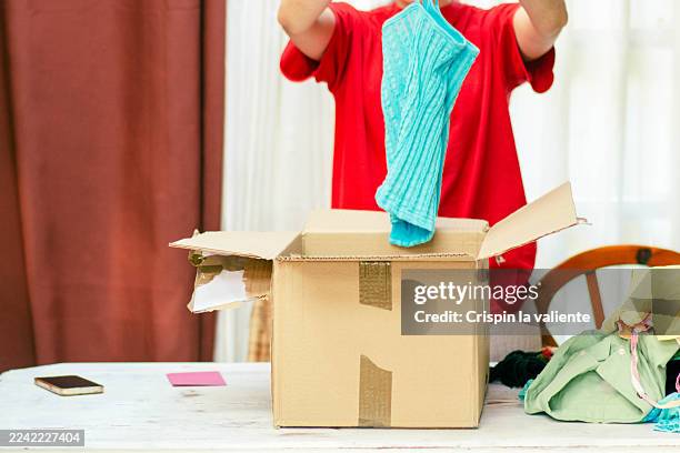 person sorting clothes for donation into cardboard box - selfless stock pictures, royalty-free photos & images