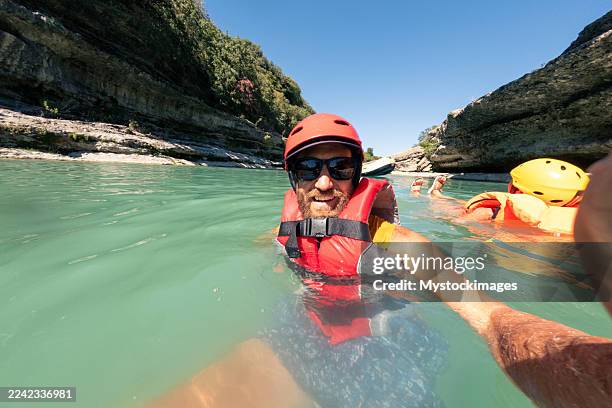 homme et partenaire nageant dans la rivière avec des casques - casque de protection au sport photos et images de collection