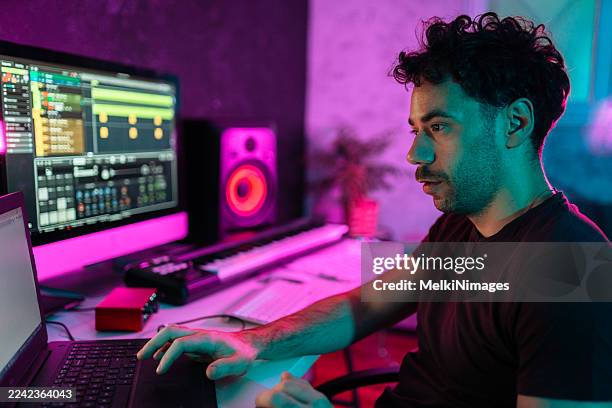 music producer working on laptop in neon studio - songwriter stock pictures, royalty-free photos & images