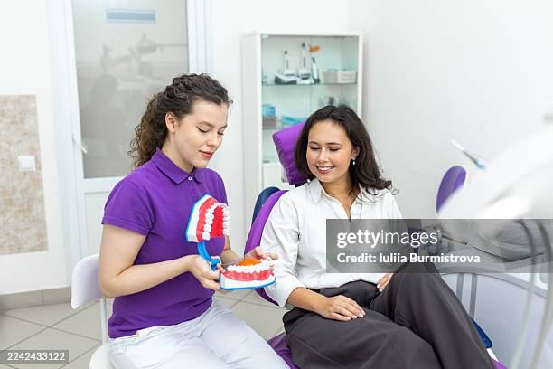 dental assistant explains dental model to patient in modern clinic chair during visit - dentin stock pictures, royalty-free photos & images