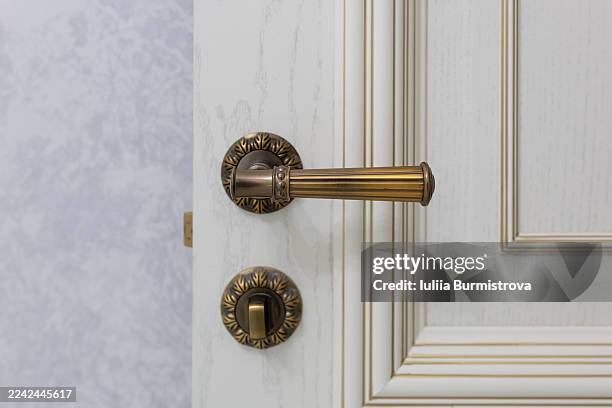 elegant brass door handle on an ornate white interior door with decorative trim - latch stock pictures, royalty-free photos & images
