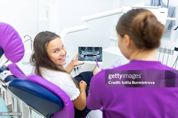young patient and dentist review a dental x-ray during a pediatric dental visit in a bright clinic - dentin stock pictures, royalty-free photos & images