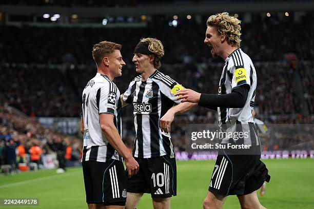 Harvey Barnes of Newcastle United celebrates scoring his team's third goal with teammates Anthony Gordon and Nick Woltemade during the UEFA Champions...