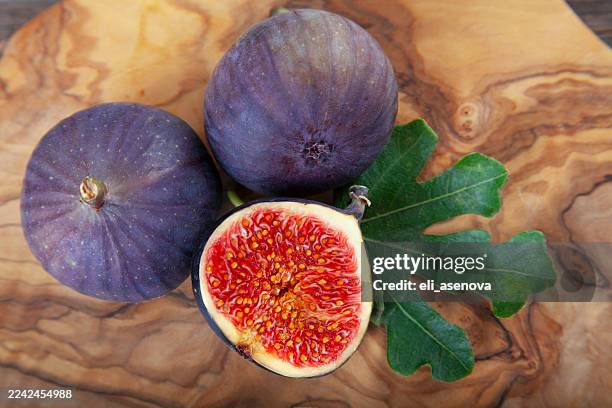 raw sweet figs with leaves on cutting board on a wooden rustic background closeup. - geheel stockfoto's en -beelden