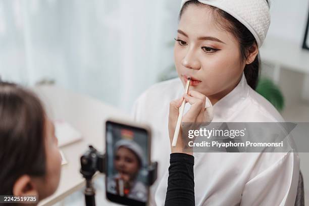 make-up artist applying lipstick with precision with lip brush on asian bride lips. beautician recording lipstick application process with smartphone. beauty care, expertise, and influencer lifestyle. - tutorial stock pictures, royalty-free photos & images