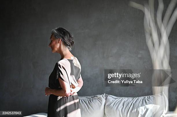 mujer mayor contemplando la vida en un hogar urbano minimalista - arte minimalista fotografías e imágenes de stock