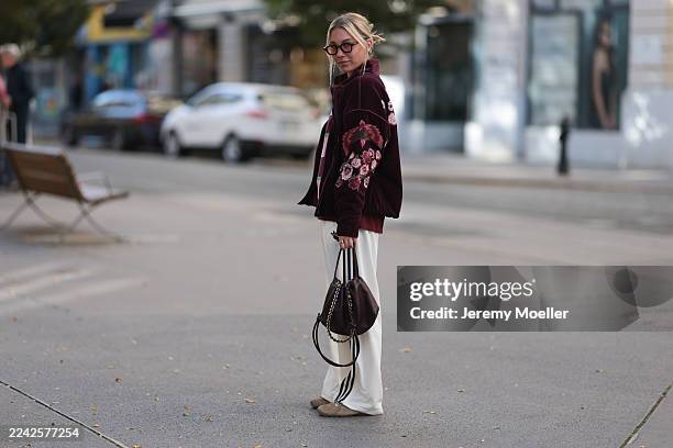 Karin Teigl with blonde straight and short hair seen wearing a Zara burgundy velvet jacket featuring a subtle floral pattern, layered over a Prada...