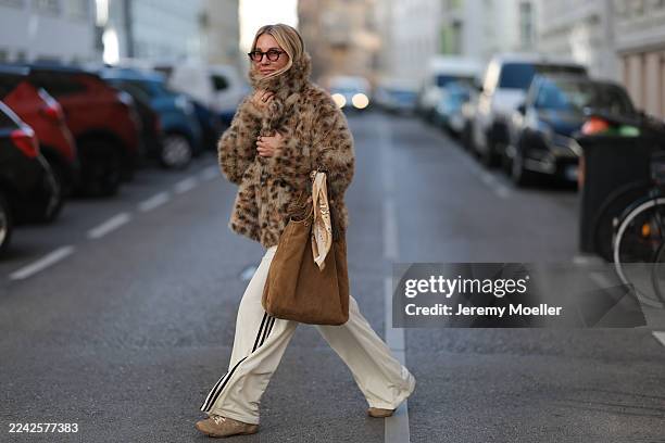 Karin Teigl with blonde short and straight hair seen wearing a statement Munthe faux fur jacket in a bold leopard print, layered over a Miu Miu...