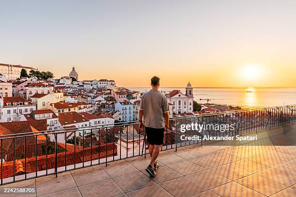 rear view of a man watching sunrise from portas do sol miradouro in lisbon, portugal - wonderlust imagens e fotografias de stock