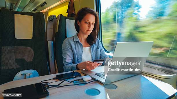 empresaria está haciendo un pago en línea mientras trabaja de forma remota en un tren. - espacio de trabajo virtual compartido fotografías e imágenes de stock