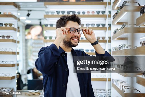 Uomo che seleziona occhiali da vista in negozio di ottica Uomo che seleziona occhiali da vista in negozio di ottica