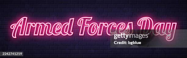 armed forces day - glowing neon text on brick wall background - armed forces day stock illustrations